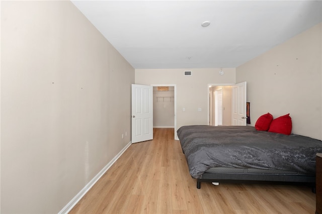 bedroom featuring light wood-style flooring, visible vents, and baseboards