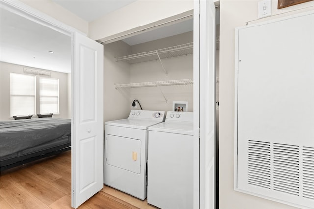 clothes washing area with light wood-type flooring, laundry area, and washing machine and clothes dryer