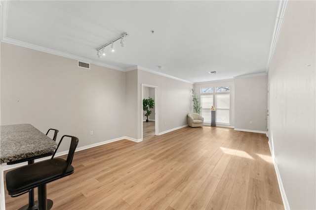 office with ornamental molding, light wood-type flooring, visible vents, and baseboards