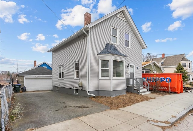 view of front of property with a garage, a chimney, fence, and an outdoor structure