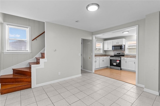 kitchen with white cabinets, light tile patterned floors, baseboards, and stainless steel appliances