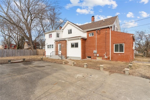 view of front of home with brick siding, fence, and a chimney