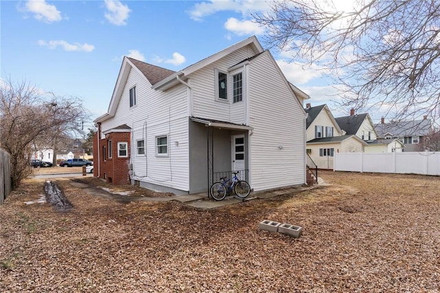 rear view of house with brick siding and fence