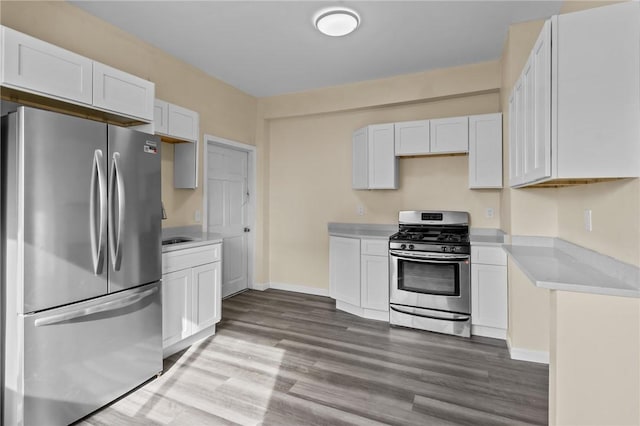 kitchen with baseboards, appliances with stainless steel finishes, dark wood-type flooring, light countertops, and white cabinetry