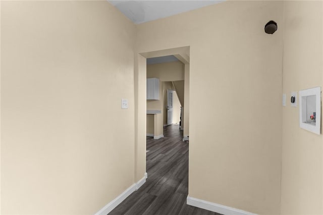 hall with dark wood-style flooring and baseboards