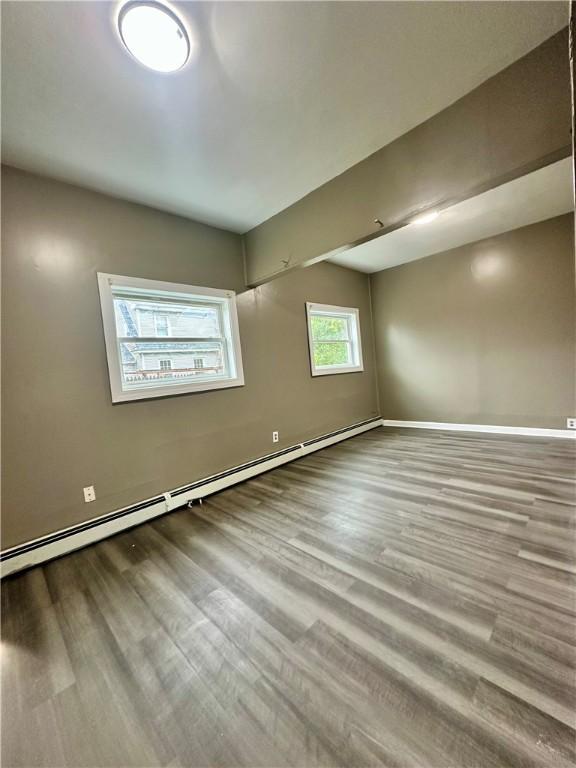 spare room with a baseboard heating unit, baseboards, and wood finished floors