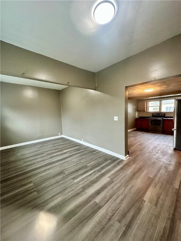 empty room with vaulted ceiling, baseboards, and wood finished floors