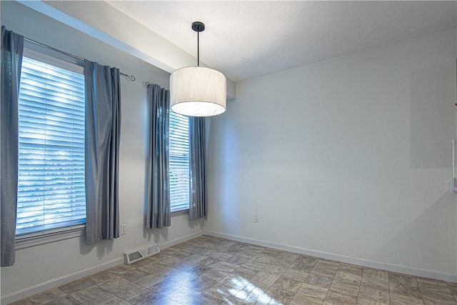 unfurnished room with visible vents and baseboards