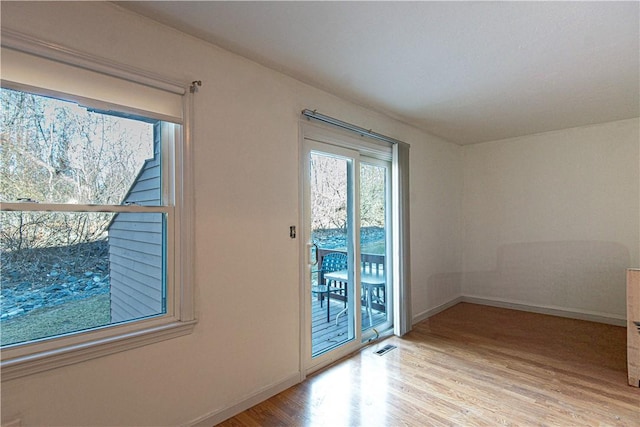 spare room featuring visible vents, baseboards, and wood finished floors