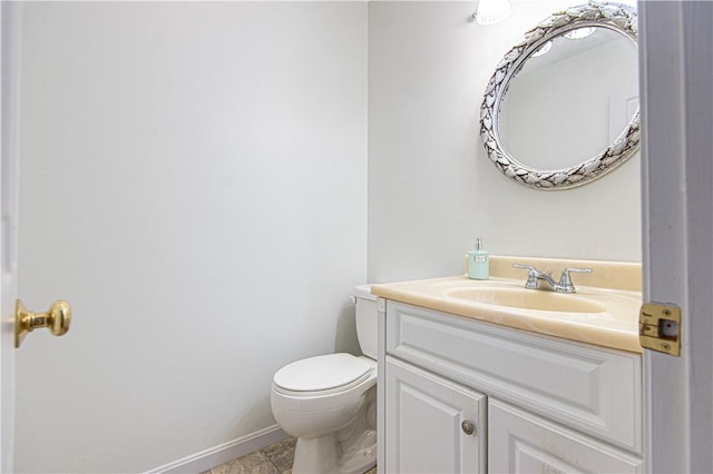 bathroom featuring toilet, baseboards, and vanity