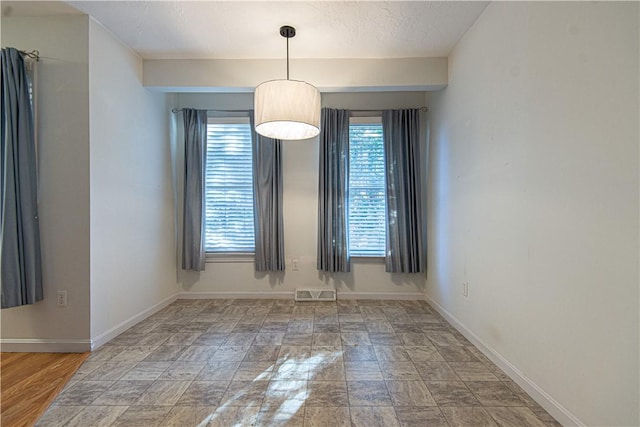 empty room featuring a textured ceiling, visible vents, and baseboards