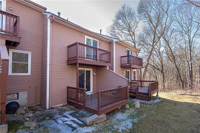 rear view of property featuring a balcony and a lawn