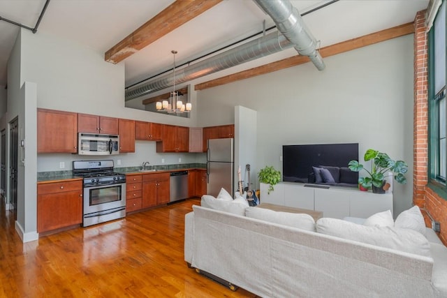 kitchen featuring appliances with stainless steel finishes, open floor plan, brown cabinetry, and a sink