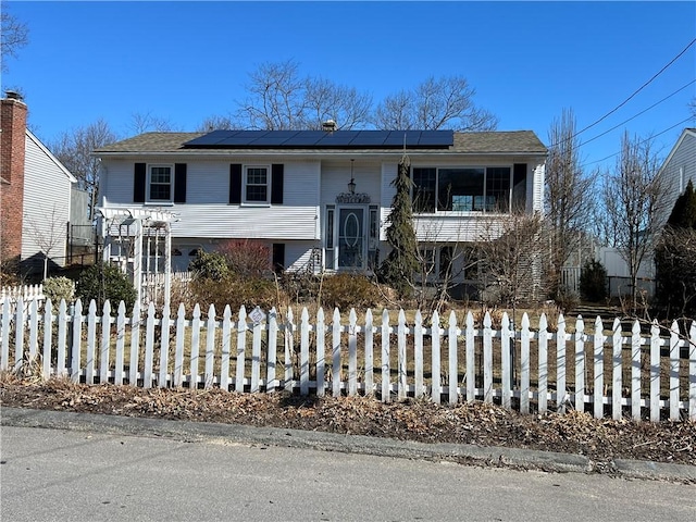 bi-level home with a fenced front yard and roof mounted solar panels