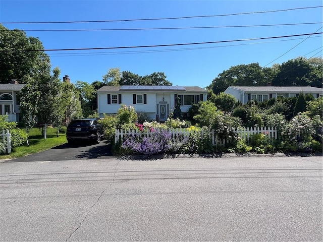 view of front facade featuring roof mounted solar panels and driveway