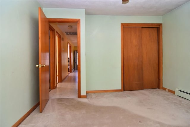 unfurnished bedroom featuring baseboard heating, baseboards, and carpet