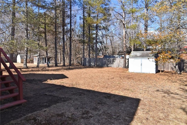 view of yard with an outbuilding, fence, and a shed