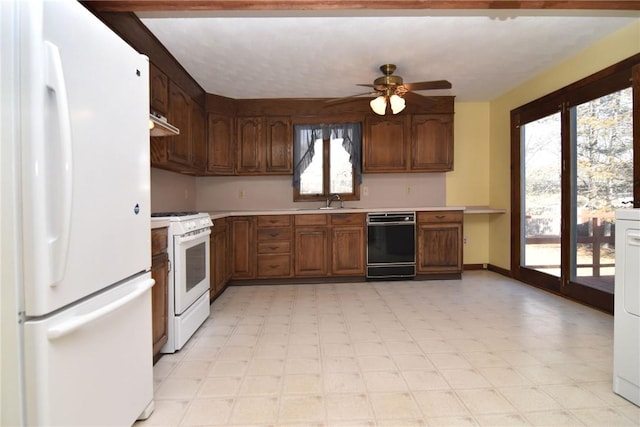 kitchen with a ceiling fan, a sink, white appliances, light countertops, and light floors