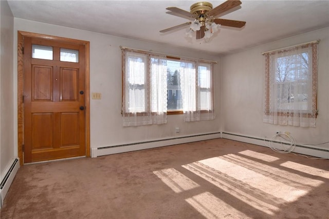 foyer entrance with a baseboard heating unit, a ceiling fan, a healthy amount of sunlight, and carpet flooring