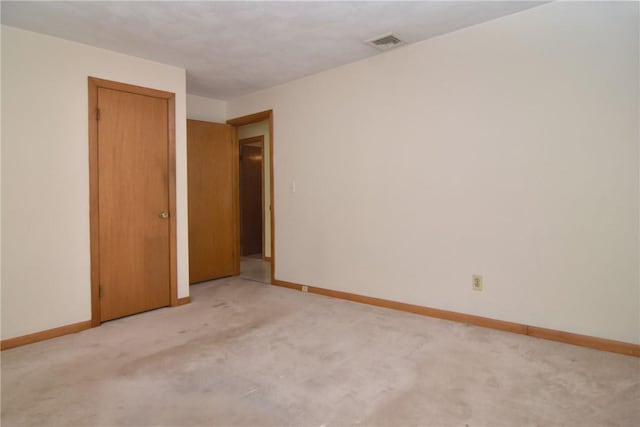 spare room with baseboards, visible vents, and light carpet