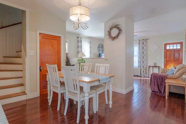 dining area featuring a notable chandelier, wood-type flooring, stairway, radiator heating unit, and baseboards