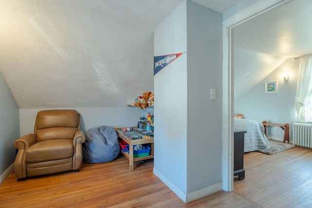 rec room with lofted ceiling, radiator heating unit, baseboards, and wood finished floors