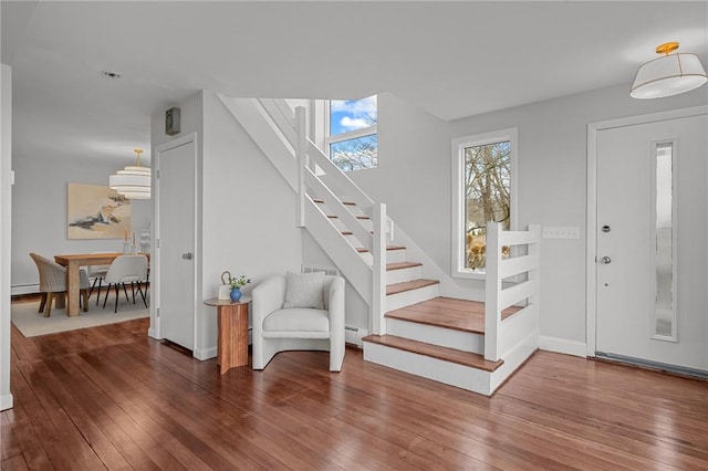 entryway with a baseboard heating unit, hardwood / wood-style floors, and stairs