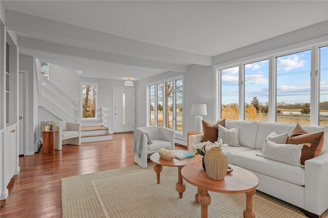 living room with stairway, wood-type flooring, and plenty of natural light