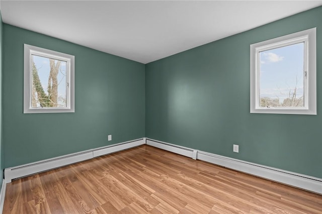 unfurnished room featuring a baseboard radiator, baseboards, and wood finished floors