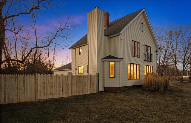 view of side of home featuring a lawn, a chimney, and fence