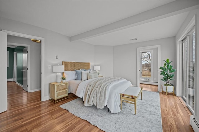 bedroom with visible vents, beamed ceiling, a baseboard radiator, and wood finished floors