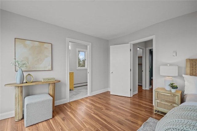 bedroom with a baseboard radiator, baseboards, and wood finished floors