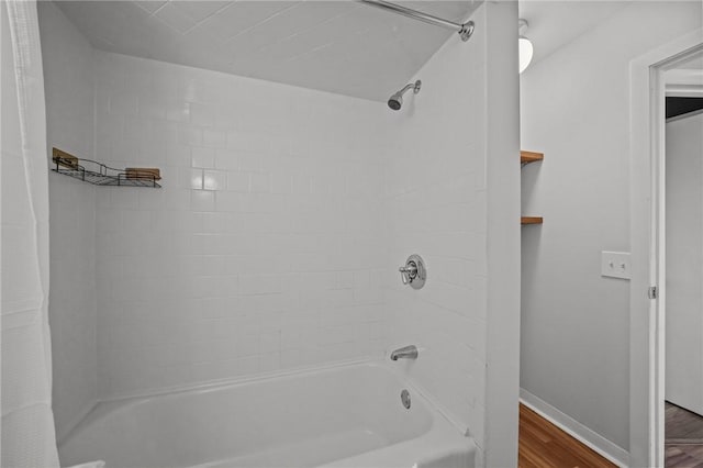 full bathroom featuring baseboards, wood finished floors, and shower / tub combo