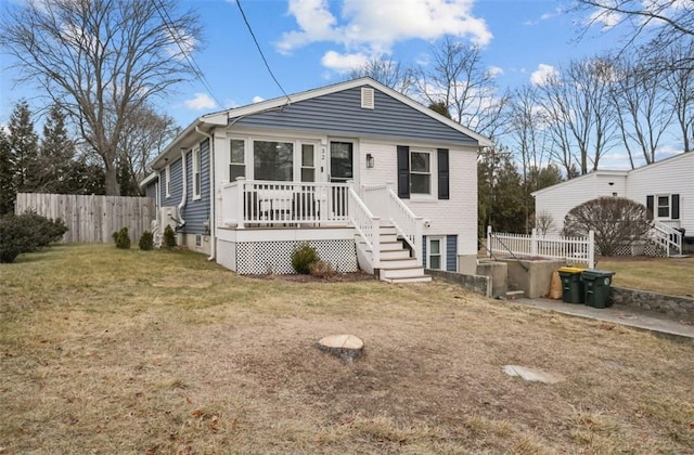 view of front of house with a deck, a front lawn, and fence