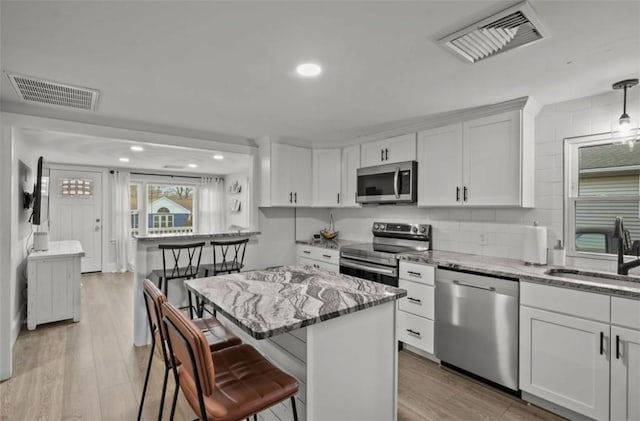 kitchen with light wood-type flooring, visible vents, stainless steel appliances, and a sink