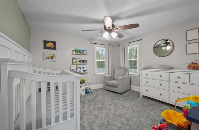 carpeted bedroom with a nursery area, baseboards, and a ceiling fan