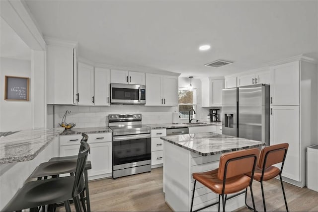 kitchen with appliances with stainless steel finishes, a breakfast bar, visible vents, and a sink