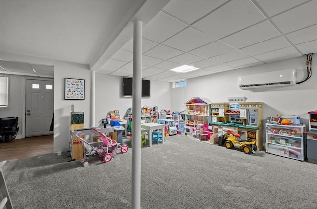 recreation room with a wall unit AC, carpet floors, and a drop ceiling