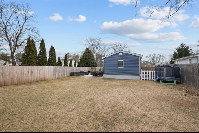 view of yard with an outbuilding, a patio, a trampoline, and a fenced backyard