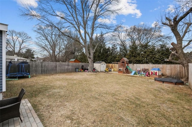 view of yard with a storage shed, a fenced backyard, a trampoline, an outdoor structure, and a playground