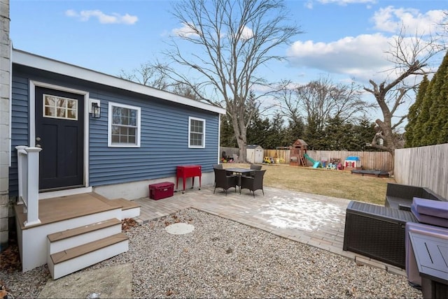 view of patio / terrace featuring a fenced backyard, a playground, and an outbuilding