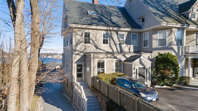 back of house featuring a chimney and stucco siding