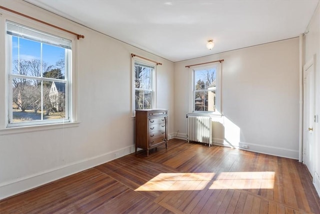 unfurnished bedroom featuring wood-type flooring, baseboards, and radiator heating unit