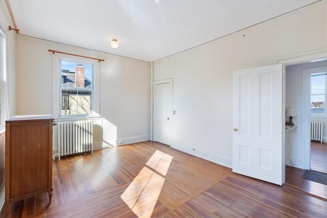 spare room with radiator, plenty of natural light, and wood finished floors