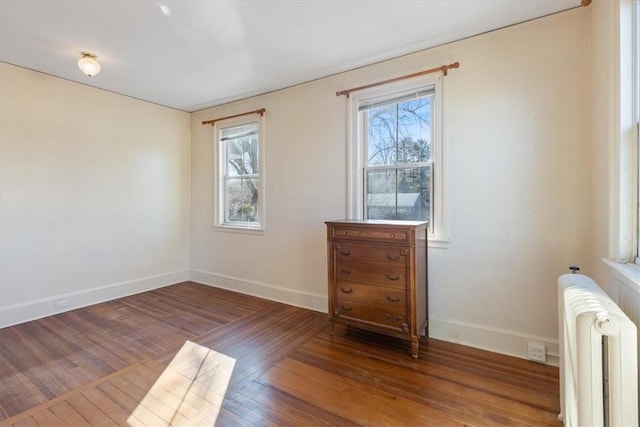 unfurnished room featuring radiator heating unit, wood finished floors, and baseboards