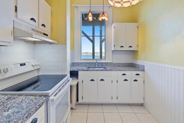 kitchen featuring electric stove, wainscoting, white cabinetry, and under cabinet range hood