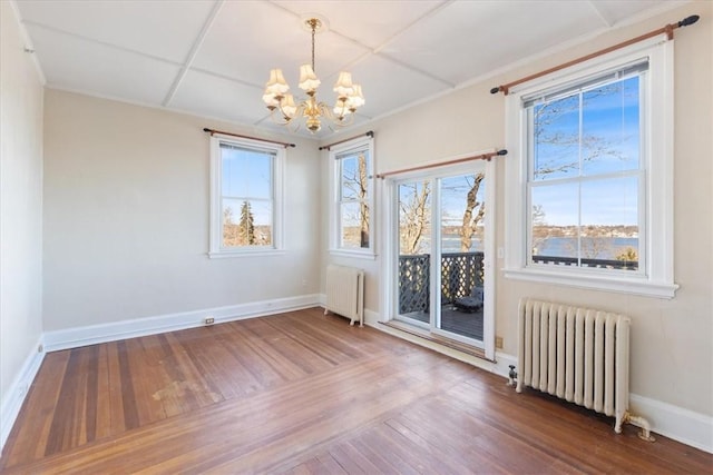 unfurnished dining area featuring a notable chandelier, radiator heating unit, and wood finished floors