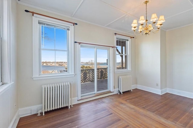 unfurnished room featuring a notable chandelier, radiator heating unit, baseboards, and wood finished floors