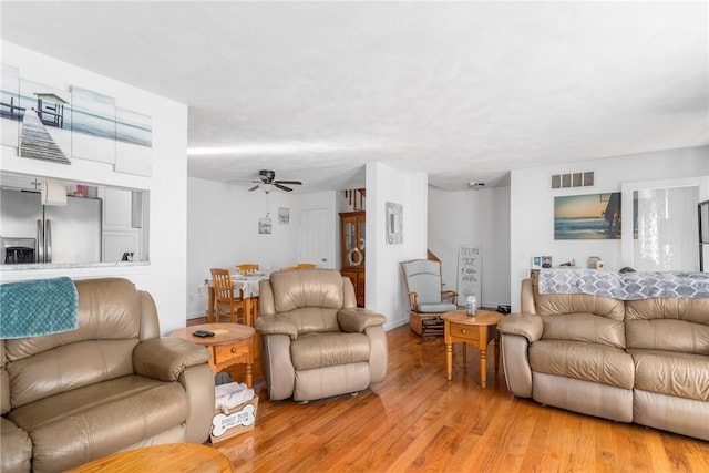 living area with baseboards, ceiling fan, visible vents, and wood finished floors