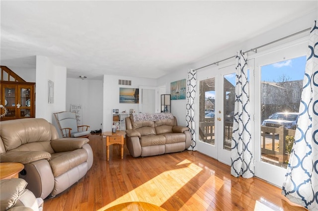 living area featuring light wood-type flooring, french doors, and visible vents